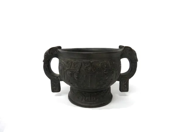 A Chinese bronze small censer or wine cup, the exterior cast with taotie masks and set with animal mask handles, measuring 10cm. across the handles.