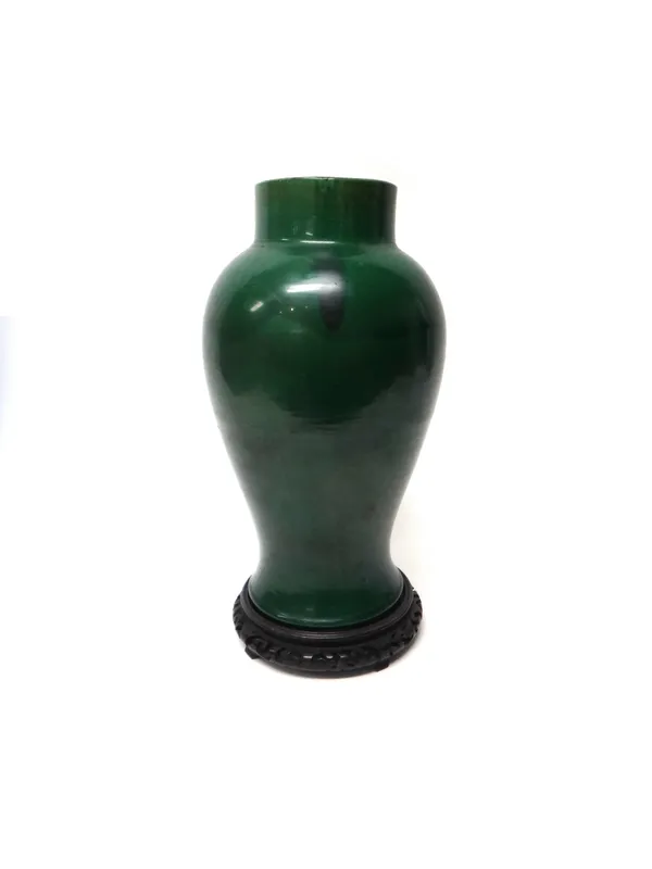 A Chinese porcelain vase,19th/20th century, of baluster form and covered in a green glaze, 39cm. high, with a wood stand.