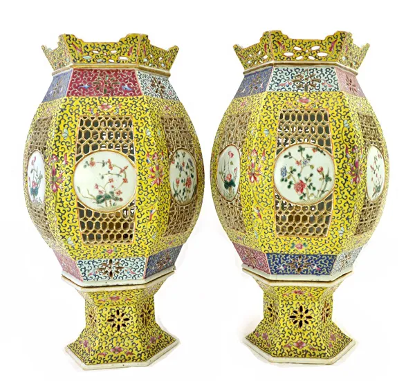 A pair of Chinese yellow ground famille-rose reticulated lanterns and stands, late 19th/early 20th century, of hexagonal barrel form, each painted wit