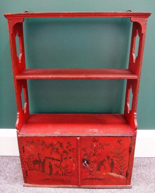 A red lacquer three tier wall shelf with pierced sides and lower cupboards, 45cm wide.