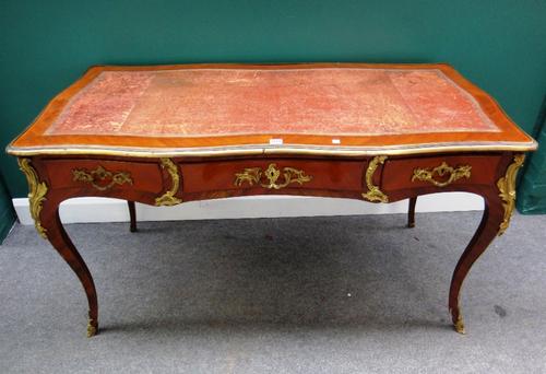 A late 19th century gilt metal mounted mahogany bureau plat of Louis XV design with serpentine top with three frieze drawers and opposing dummy drawer