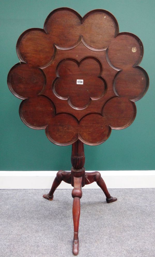 An 18th century style occasional table, the scalloped carved shaped circular snap top on a carved and turned column and three Manx feet supports, 69cm