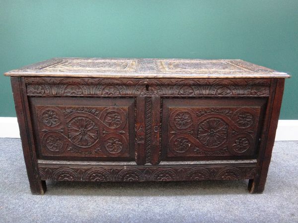 A 17th century oak coffer with a carved double panel lid and front on stile feet, 110cm wide