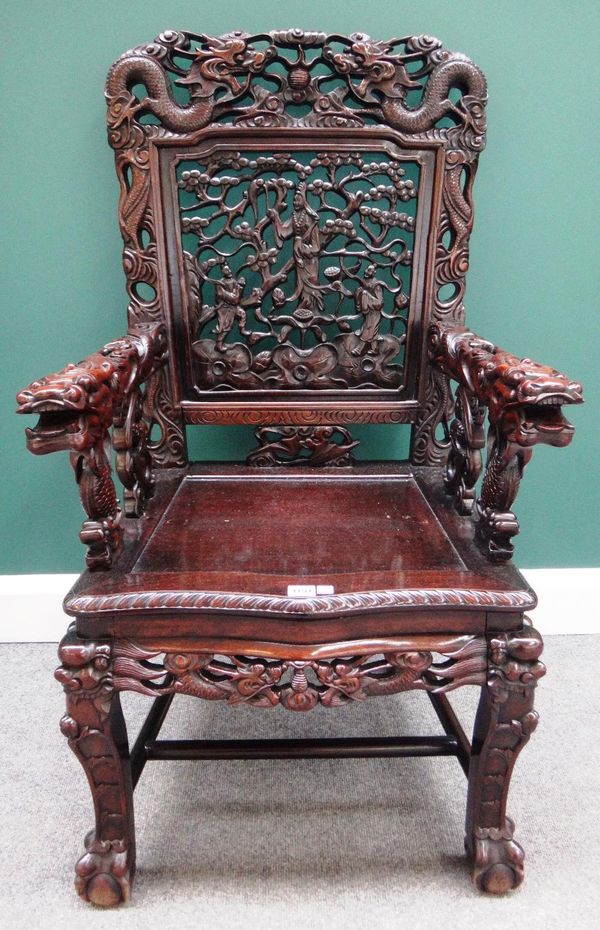 An early 20th century profusely carved Chinese hardwood open armchair, with serpentine seat on claw and ball feet.