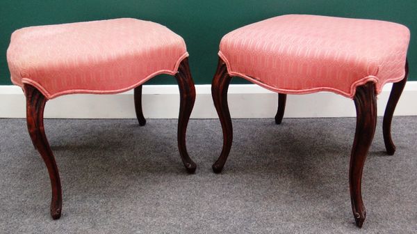 A pair of Victorian mahogany framed footstools of serpentine outline, on cabriole supports, 50cm wide.