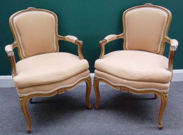 A pair of Louis XV style cream painted, open arm fauteuils, with serpentine seat on cabriole supports.