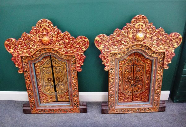 A pair of profusely carved, painted and gilded Tibetan windows, each with a pair of doors, 88cm wide x 111cm high.