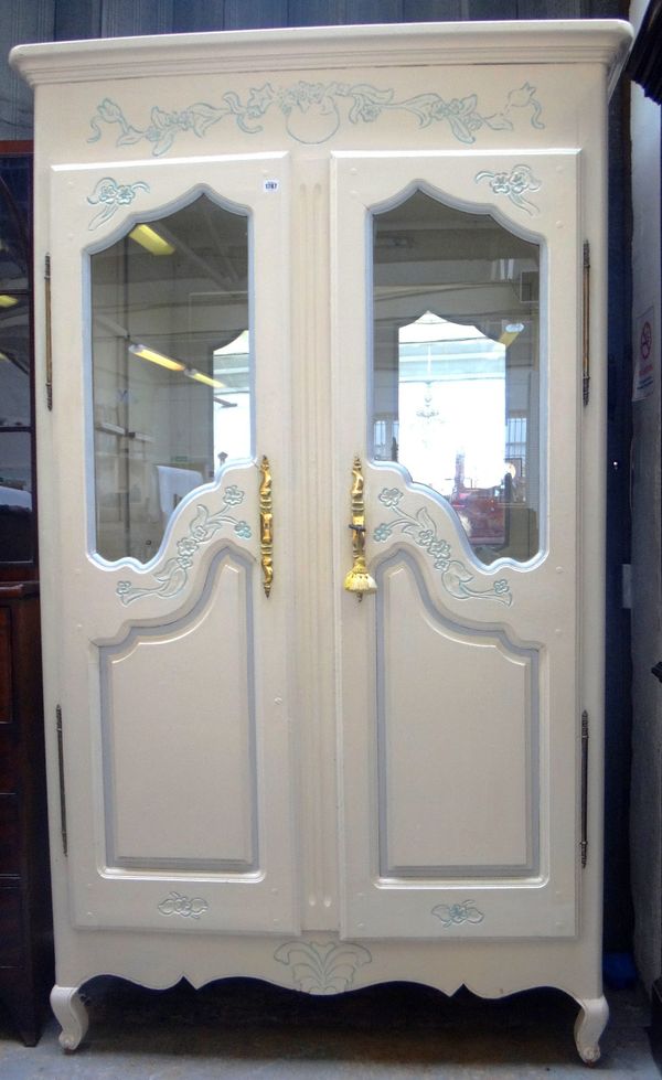 A cream and blue painted French two door armoire with semi-glazed panels, on squat cabriole supports, 129cm wide x 216cm high.