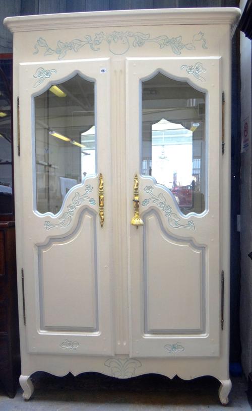 A cream and blue painted French two door armoire with semi-glazed panels, on squat cabriole supports, 129cm wide x 216cm high.