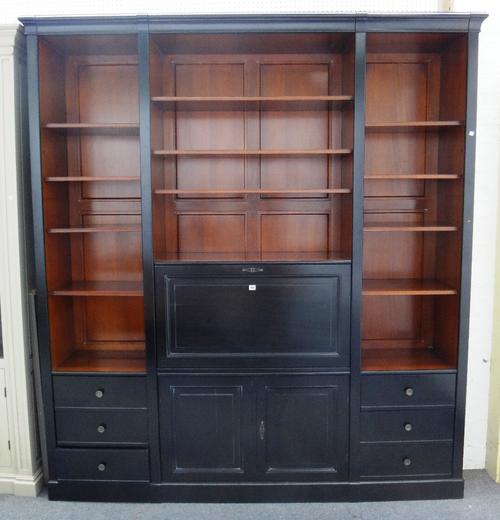 A 20th century ebonised bookcase, with an arrangement of open shelves and drawers, centred by a drop flap writing compartment, 223cm wide x 243cm high