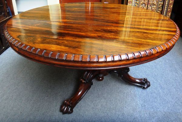 A Victorian rosewood dining table, the circular dentil moulded snap top on turned column and three downswept supports, with carved lions paw feet, 137