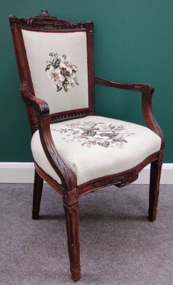 An 18th century French walnut framed open arm fauteuil with serpentine feet on tapering square supports.