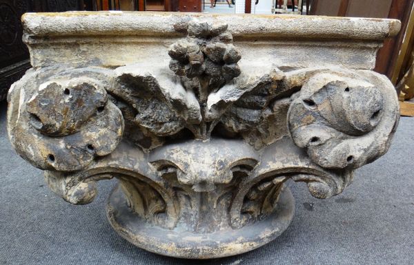 A circular glass topped coffee table, raised on a carved sandstone Corinthian column capital, 122cm wide.