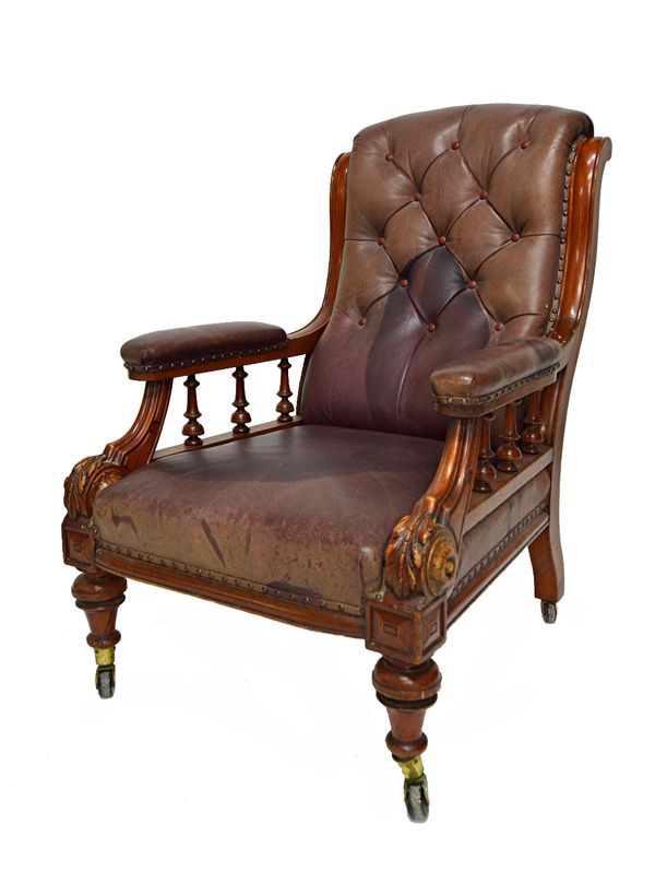 A Victorian mahogany framed open arm library chair with button rouge leather upholstery on turned front supports.   Illustrated