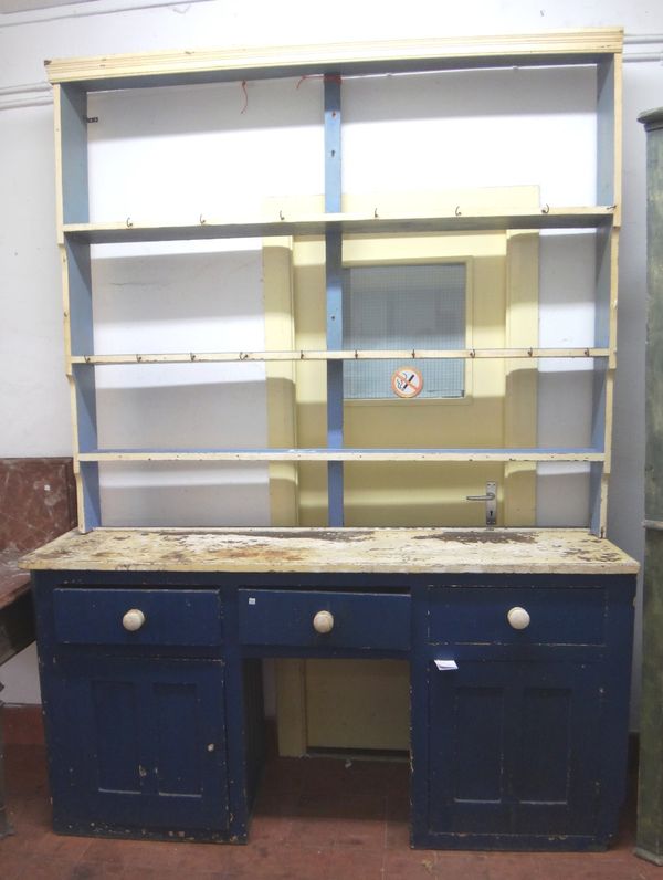 A Victorian painted pine dresser, the open three tier plate rack over three frieze drawers and a pair of cupboards, centred by a dog kennel recess, 18