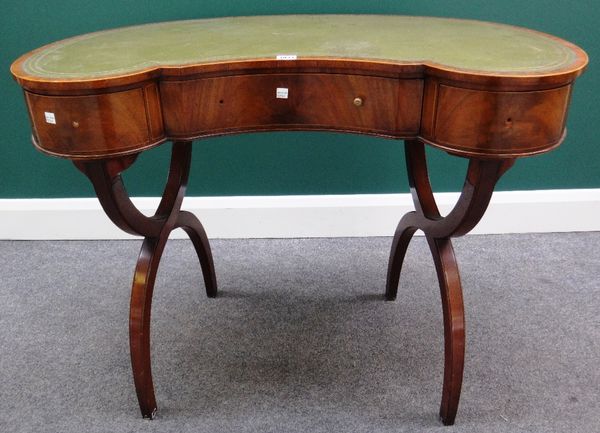 An early 20th century mahogany kidney shaped writing table with three frieze drawers on X-frame supports, 94cm wide.