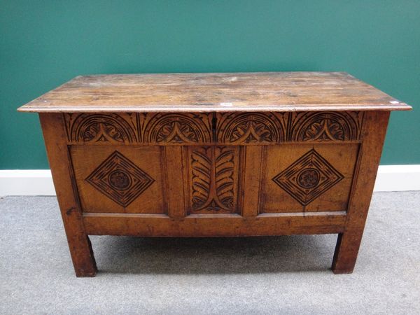 A 17th century oak coffer, with plank top over carved triple panel front, on stile feet, 112cm wide.