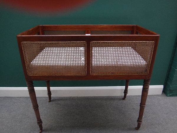 An early 19th century mahogany framed cot, with cane panels on turned supports, 102cm wide.