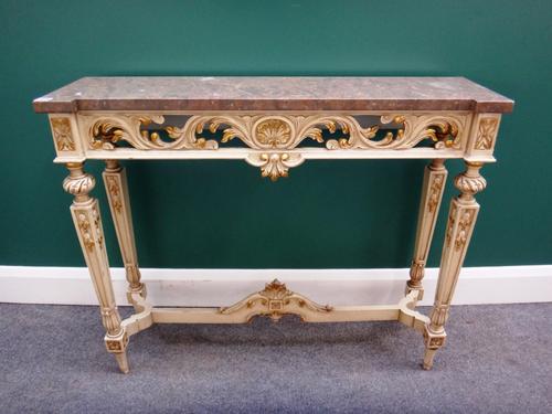 A 20th century console table, the inverted breakfront marble top on a cream and parcel gilt painted, pierced and carved base, on tapering square suppo
