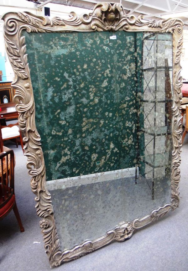 A large 19th century wall mirror, the carved and painted shaped frame with cartouche crest and Green Man mask lower frieze, 147cm wide x 203cm high ov