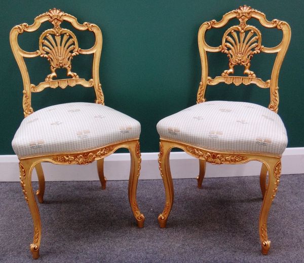 A pair of gilt framed stylised shell back side chairs with serpentine seats and cabriole supports.