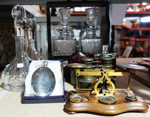 A 20th century mahogany two bottle Tantalus, a pair of decanters with silver collars, a set of postage scales, three hip flasks and binoculars. (8)