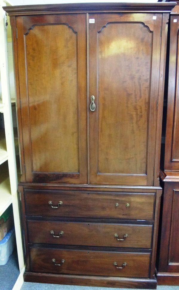 A television cabinet in the form of an 18th century mahogany linen press, the pair of panelled doors over drop front drawer and two true drawers on pl