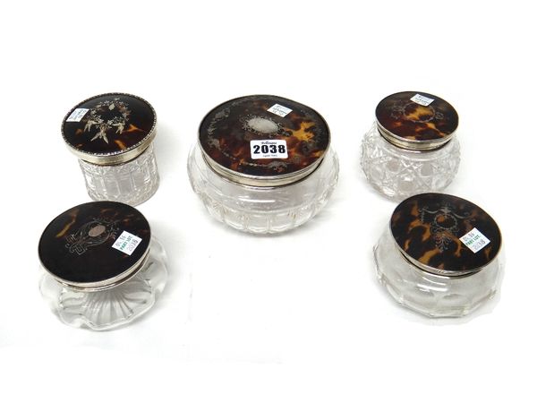 A silver mounted tortoiseshell lidded faceted glass powder jar, London 1928 and four further silver mounted tortoiseshell lidded glass powder jars, in