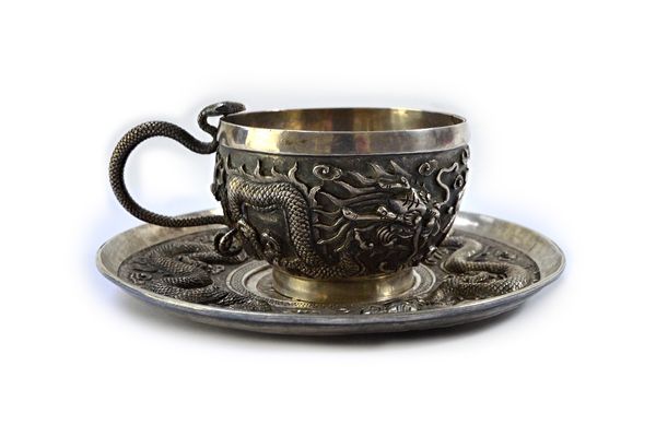 A Chinese teacup and saucer, each decorated with dragons and Chinese characters, the cup with a serpentine handle, unmarked, 180 gms.  Illustrated