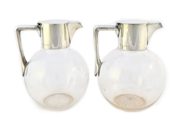 A pair of Victorian silver mounted glass claret jugs, each of globular form, with a star cut base, a hinged flat lid and with an angular handle, by He