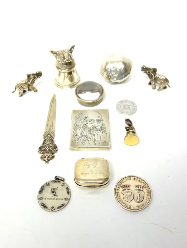A hinge lidded pill box, the cover with pale brown enamelled decoration, detailed 925, two models of elephants, detailed 800, a rectangular paperweigh