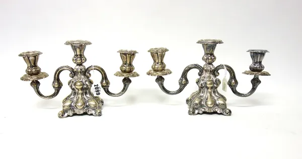 A pair of Danish three light table candelabra, each with scrolling arms and on a shaped square base, loaded, 18cm high.
