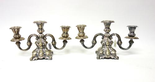 A pair of Danish three light table candelabra, each with scrolling arms and on a shaped square base, loaded, 18cm high.