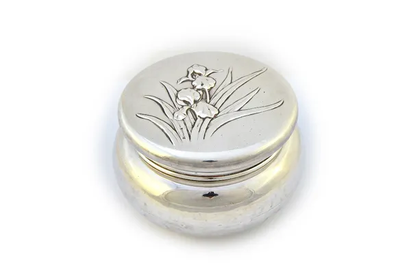 A silver circular box and cover, the cover embossed with irises, maker William Comyns, London 1904, weight 223 gms.  Illustrated
