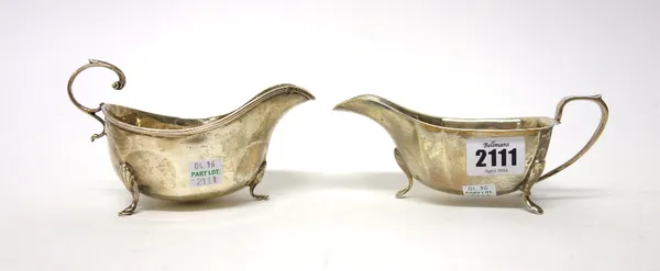 A silver sauceboat, of angular design, raised on three feet, Sheffield 1938 and another silver sauceboat, with a scrolling handle, raised on three fee