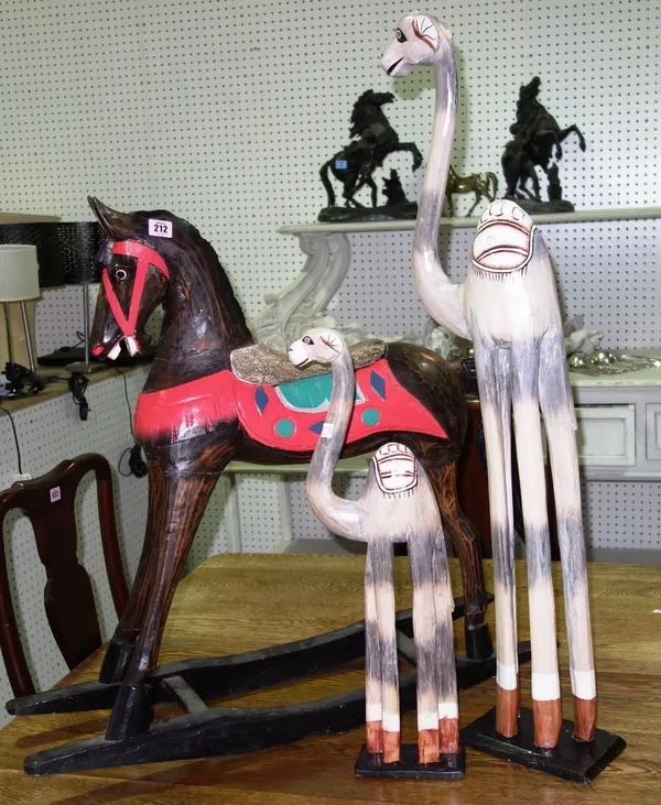 A 20th century black painted wooden rocking horse and two carved wooden camels. (3)