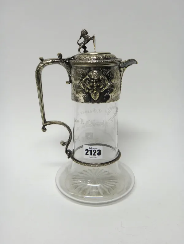 A Victorian silver plated metal mounted glass claret jug, the hinged lid with a lion and a shield thumbpiece, the mount otherwise decorated with masks