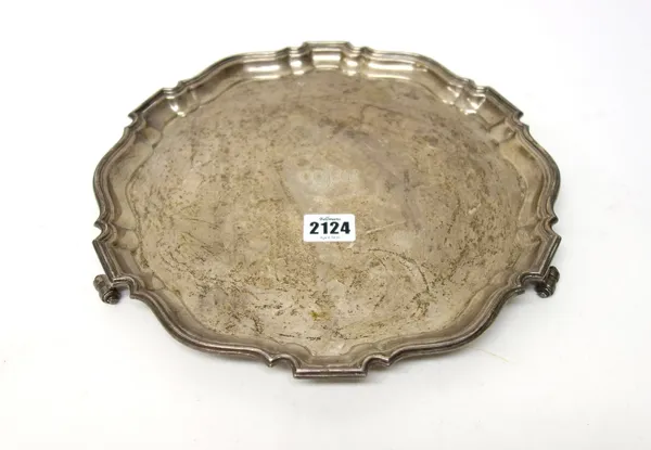 A silver salver, of shaped circular form, with a Chippendale style rim, raised on three scrolling feet, in the 18th century taste, inscribed and dated