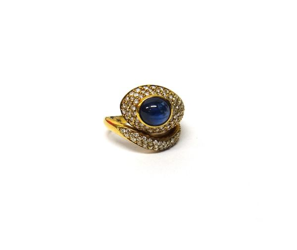 A gold, cabochon sapphire and diamond set ring, in a stylized serpentine design, mounted with an oval cabochon sapphire and otherwise set with small c