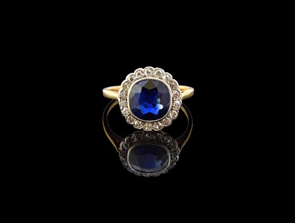 A gold, sapphire and diamond set cluster ring, mounted with the cushion shaped sapphire at the centre, within a surround of small cushion shaped diamo