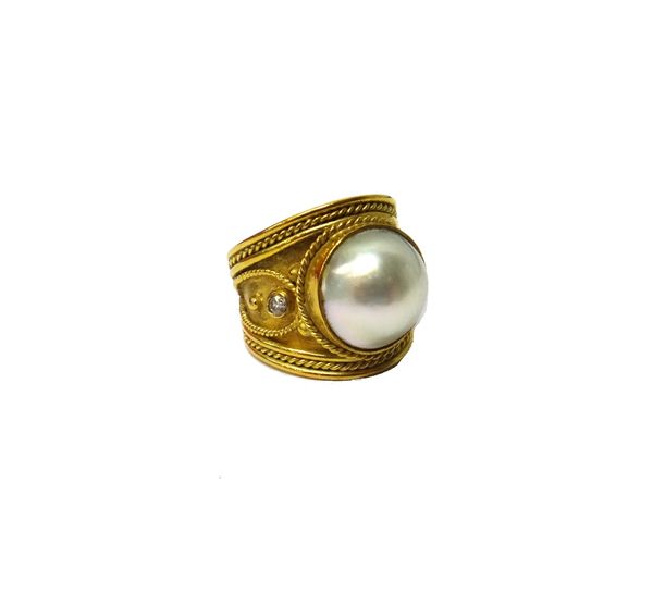 A gold, diamond and mabe pearl set ring, mounted with the large mabe pearl at the centre, between two circular cut diamonds, the mount in a Hellenisti