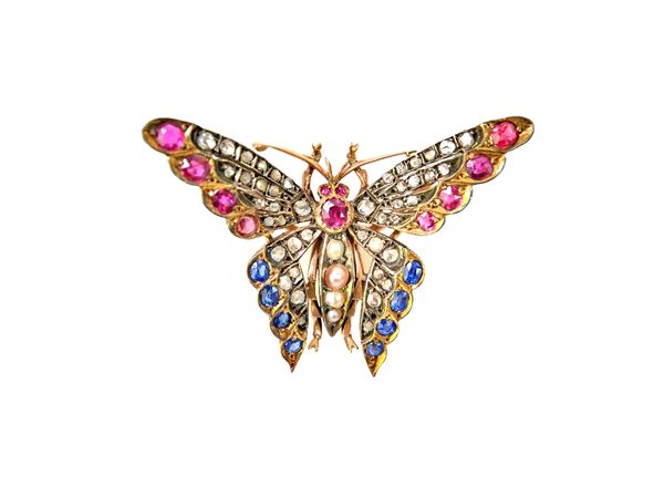 A gold and silver set rose diamond, sapphire, ruby, half pearl and gem set brooch, designed as a butterfly in flight, the back having a detachable pin