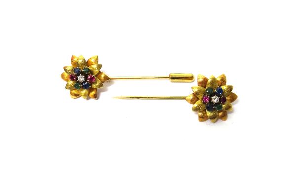 A pair of two colour gold, diamond, sapphire, ruby and emerald set pins, each with a flowerhead terminal, claw set with a circular cut diamond to the