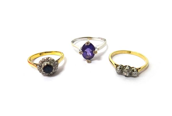 A gold, sapphire and diamond set cluster ring, detailed 18 C, a gold and diamond set three stone ring, claw set with a row of cushion shaped diamonds,