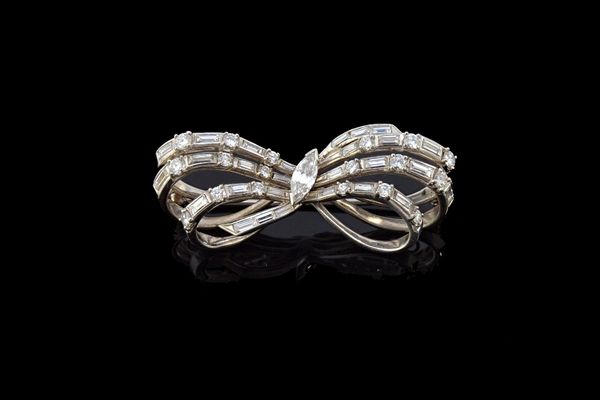 A diamond set brooch, designed as a ribbon tied bow, mounted with the principal marquise diamond at the centre and otherwise set with circular cut and