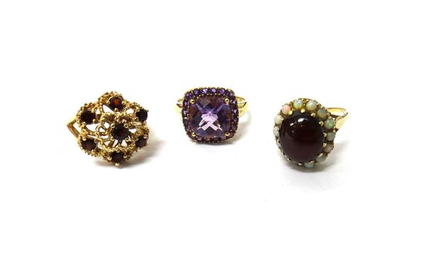 A 9ct gold ring, claw set with an oval carbuncle garnet at the centre, in a surround of circular opals, a 9ct gold and garnet set seven stone cluster