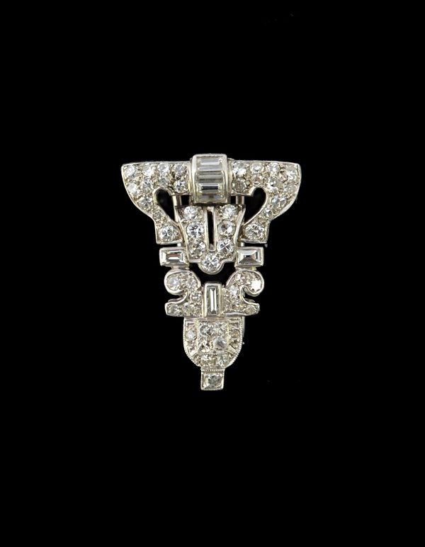 A diamond set dress clip, pierced in an Art Deco geometric design, mounted with baguette and circular cut diamonds.   Illustrated