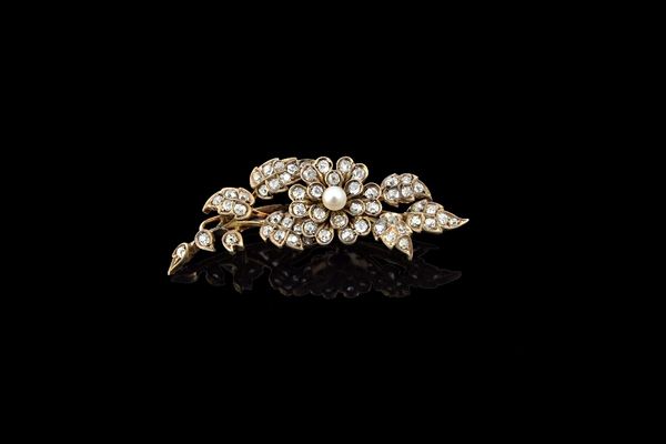 A diamond and pearl brooch, designed as a floral and foliate spray, mounted with a single pearl and otherwise set with small cushion shaped diamonds.