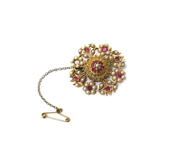 A gold, ruby and cultured pearl set brooch, in a shaped circular design, having a pierced border, with flowerhead shaped clusters at intervals (one ru