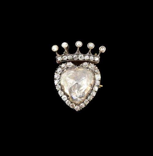 A diamond brooch, mounted with a large foil backed rose cut diamond to the centre, in a heart shaped surround set with small cushion shaped diamonds a